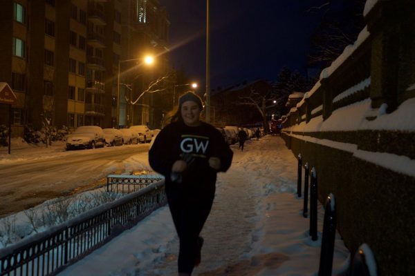 Ana running in George Washington University sweatshirt on a dark winter morning. She is smiling.