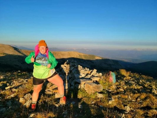 Sarah Stuhr posing on top of the mountain